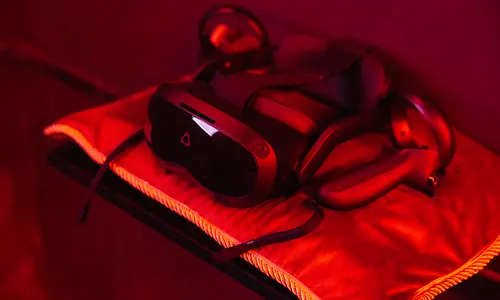 VR-headsetek és kontrollerek vörös fényben, játékra előkészítve